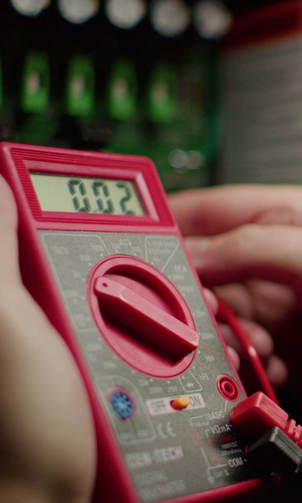 electrician working on a red tool in front of a blurry green background