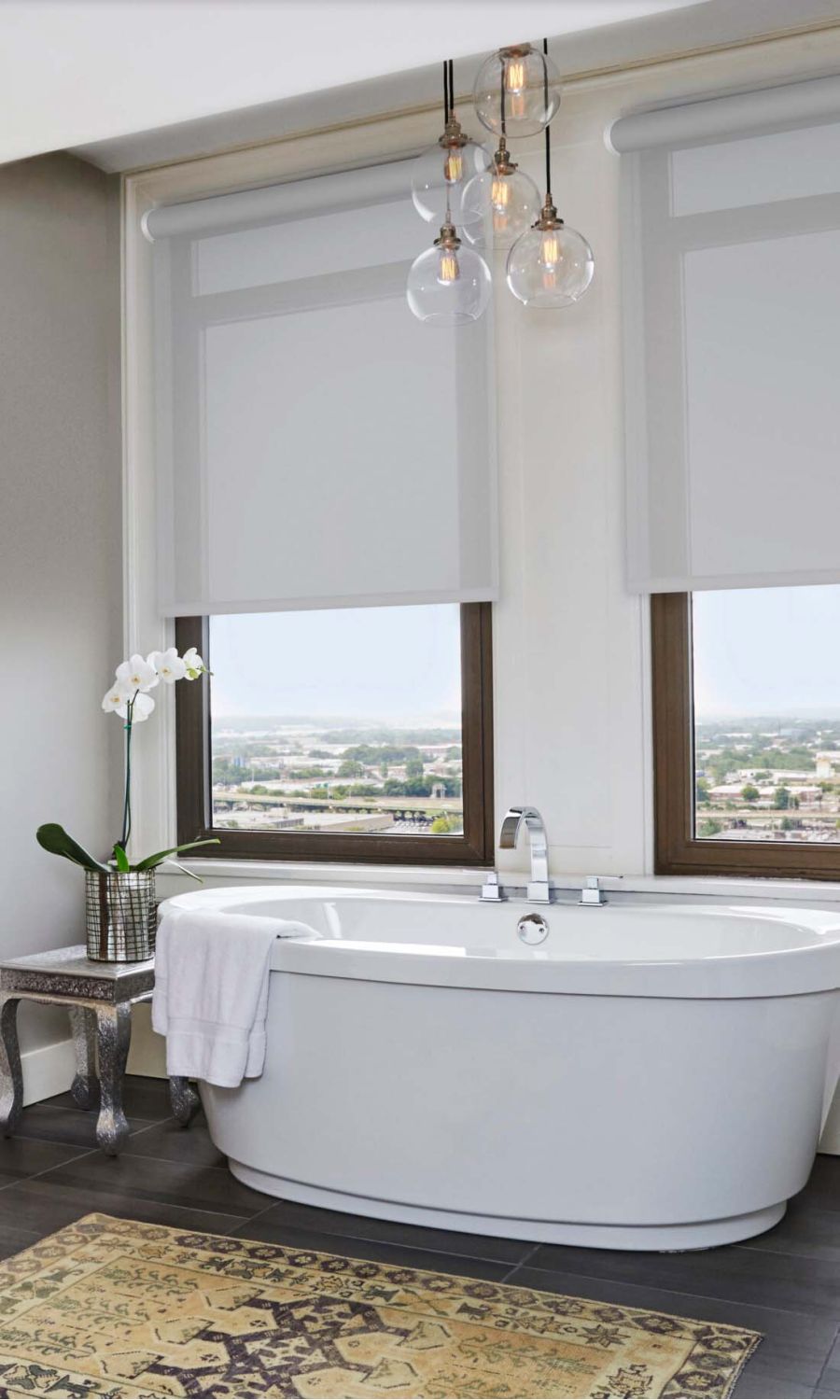 Modern living room with Lutron solar shades, a large sectional sofa, and a view of the city skyline.